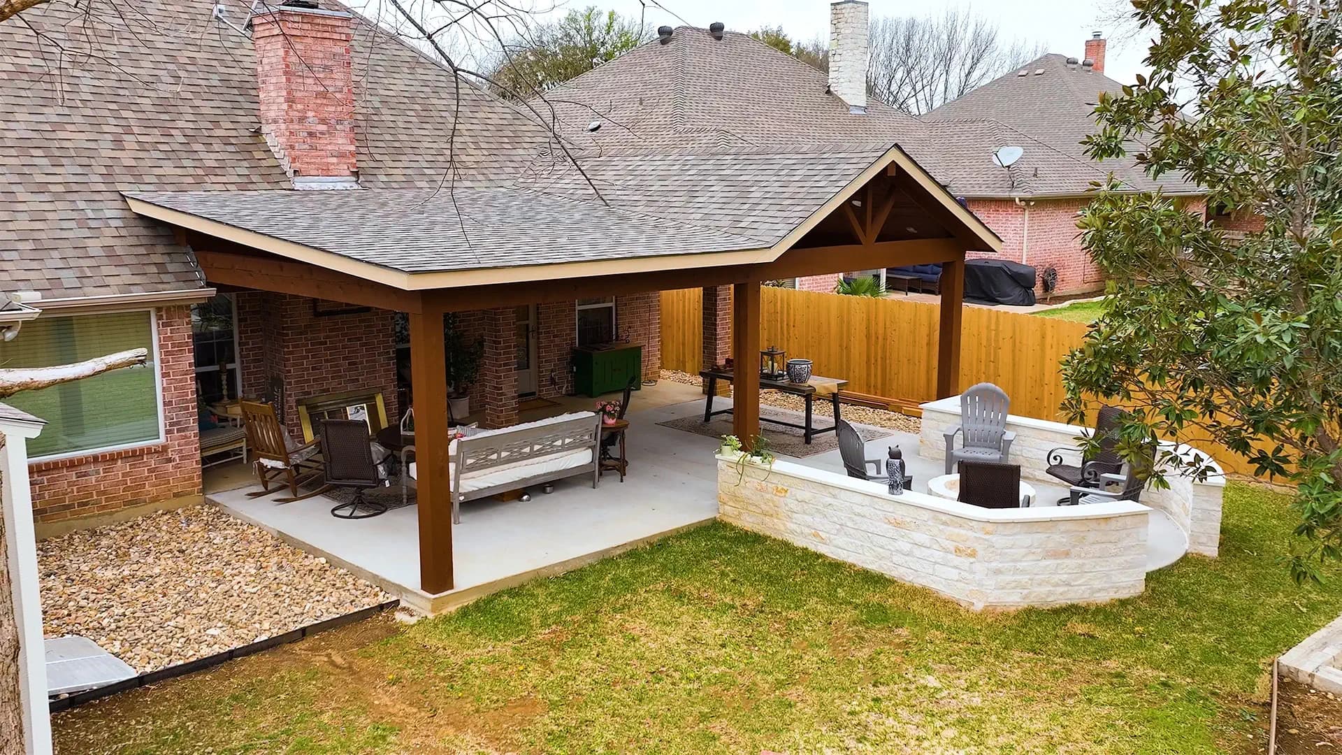 A finished covered backyard patio with a stone fire-pit seating area on a North Texas Streamline Landscape project